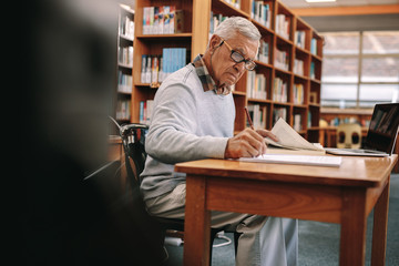 Senior man writing sitting in a university classroom