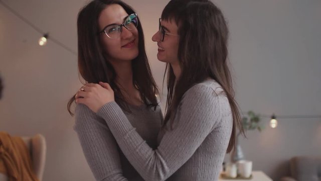 Beautiful two twins sisters with glasses together holding each other in hugs