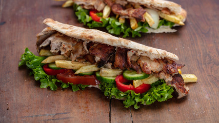 Gyros, shawarma, take away, street food.  Sandwich with meat on wooden table