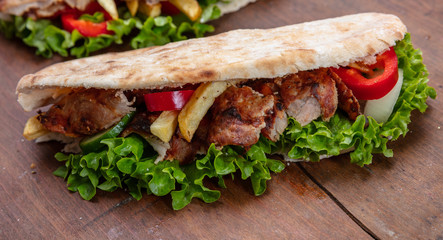 Gyros, shawarma, take away, street food.  Sandwich with meat on wooden table