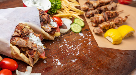 Gyro pita, shawarma, souvlaki. Two pita bread wraps and meat skewers on wooden table