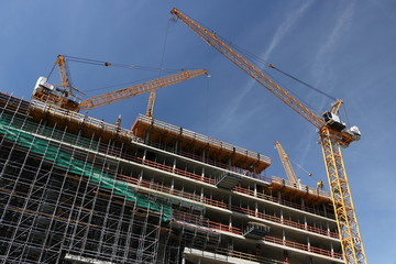 Berlin. 06/14/2008. Glass facade of a building with reflection of a construction site. Cranes and scaffolding