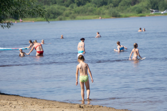 the beach showing colorful umbrellas and people bathing in the ocean on a summer day. The concept of tropical travel and recreation.