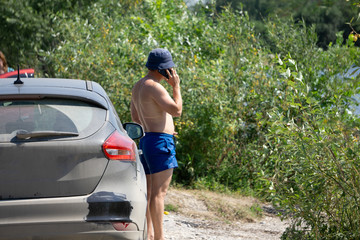 middle-aged man on vacation next to his beach vintage oldtimer car .