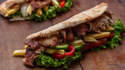 Gyros, shawarma, take away, street food.  Sandwich with meat on wooden table