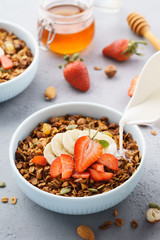 Pouring milk in a bowl of granola with strawberry and banana.