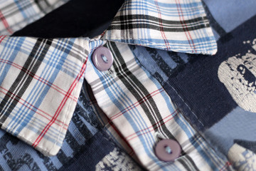 Close up of buttons and collar on a checked flannel shirt.