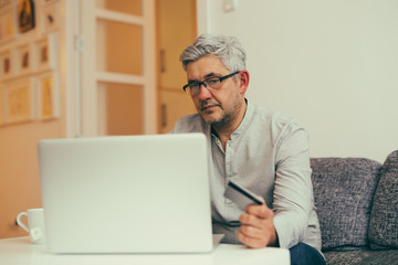middle aged man using laptop for online shopping from his apartment