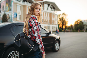 Fototapeta na wymiar Young woman driver with bag against a car