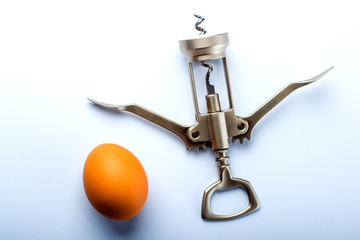 metal corkscrew and egg on light blue background