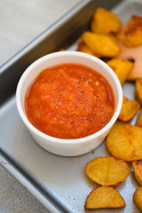 Bowl with spicy tomato salsa or mojo rojo, a red hot sauce made of roasted bell peppers, chili, onions and garlic served with patatas or papas bravas, a traditional Spanish baked potatoes tapas dish