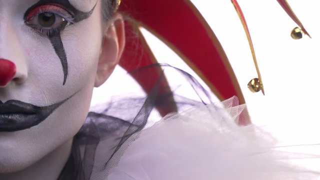 Close up of the half of jesters face, black and white makeup, looking around