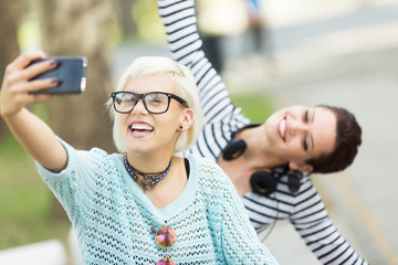 Young cute and beautiful female students taking selfies outdoors in campus
