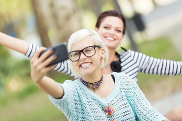 Young and cute female students taking selfies outdoors in campus