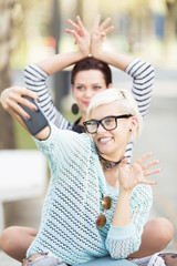 Young happy female students taking selfies outdoors in campus