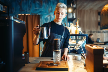 Barista pours water from coffee pot into the glass
