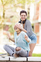 Young happy female students(one with flower tights) outdoors in campus having a good time