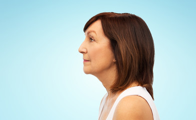Fototapeta premium beauty, rhinoplasty and old people concept - profile of senior woman over blue background