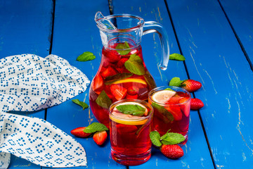 Lemonade with strawberries and lemon in a glass decanter