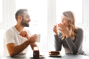 Young loving couple sitting at the kitchen have a breakfast talking with each other.