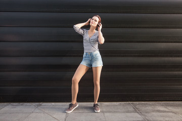 Young woman standing outdoors and holding a head speakers