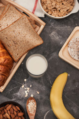 Photo of bread, bun, milk, almonds and fresh milk on table with skin color background. Breakfast preparation, daily product.