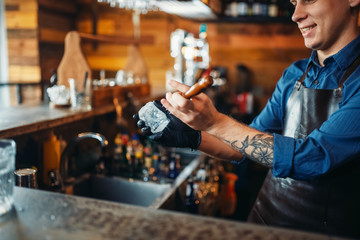 Male bartender stabs ice at the bar counter