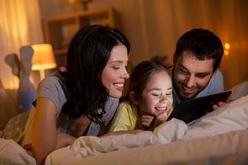people and family concept - happy mother, father and little daughter with tablet pc computer in bed at night at home