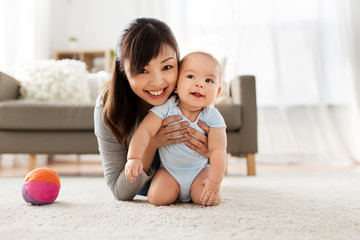 family and motherhood concept - happy smiling young asian mother with little baby at home
