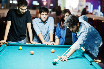 Group of stylish asian friends wear on jeans playing pool billiard on bar.