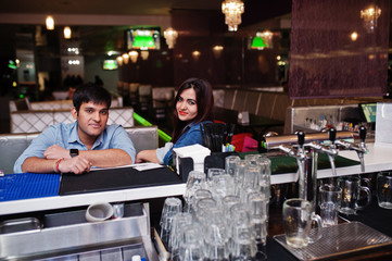 Stylish asian couple wear on jeans sitting on chair at bar in club.