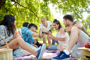 friendship and leisure concept - group of happy friends with non alcoholic drinks and food at...