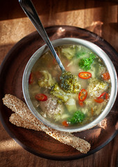 broccoli soup and meat dumplings in a plate on a wooden table