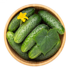 Whole cucumbers in wooden bowl isolated on white. Top view.