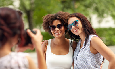 female friendship, technology and people - woman with camera photographing her friends in summer park