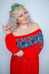 cute chubby girl with flowers in white curly hair in red rustic dress