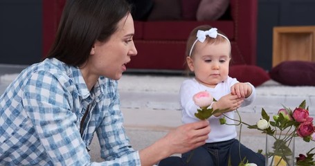 Mother and baby daughter arranging rose flowers together at home