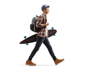 Full length profile shot of a male student walking and holding a longboard isolated on white background