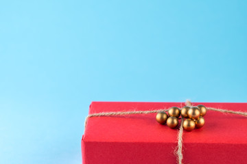 Red gift box tied with string on a bright blue background, minimalism.