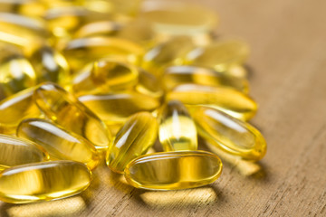 Pile of fish oil omega 3 gel capsules on wooden board