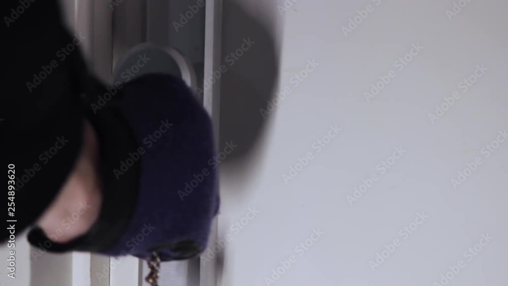 Poster close up shot of a shadowy figure opening a door with a set of keys and wearing gloves. concept of i