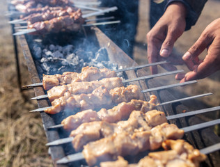 A man fries kebabs on skewers on the grill