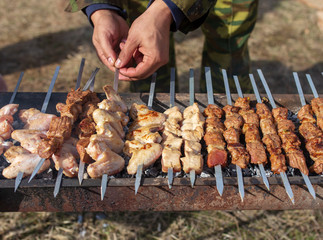 A man fries kebabs on skewers on the grill