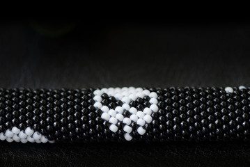 Black beaded bracelet with skull image on a dark background close up
