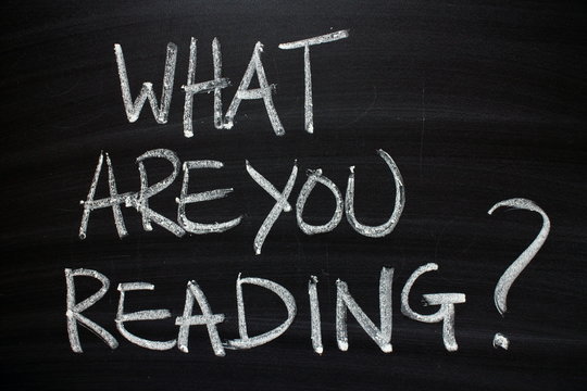 The question What Are You Reading written by hand in white chalk on a blackboard