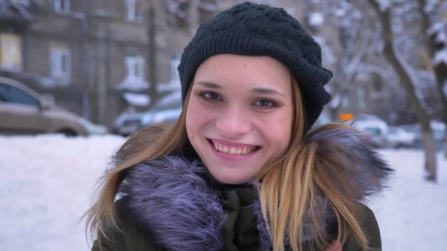 Closeup shoot of young attractive caucasian female with brunette female smiling happily while looking at camera standing outdoors in a snowy winter day