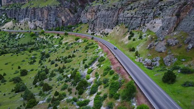 Aerial view of a vehicle driving on a dramatic cliff side road in Wyoming