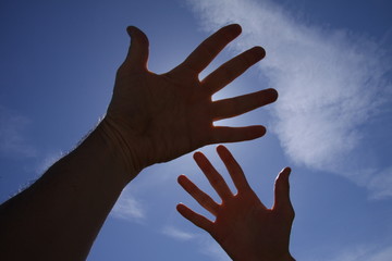 Hands reaching in the air with blue sky and light rays