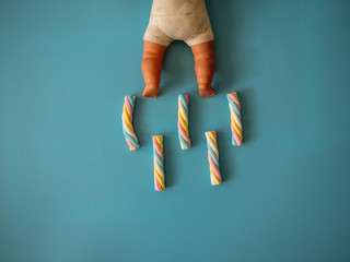 Candies with cloud shape on a sky blue background next to a baby toy