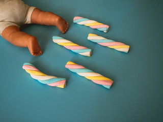 Candies with cloud shape on a sky blue background next to a baby toy